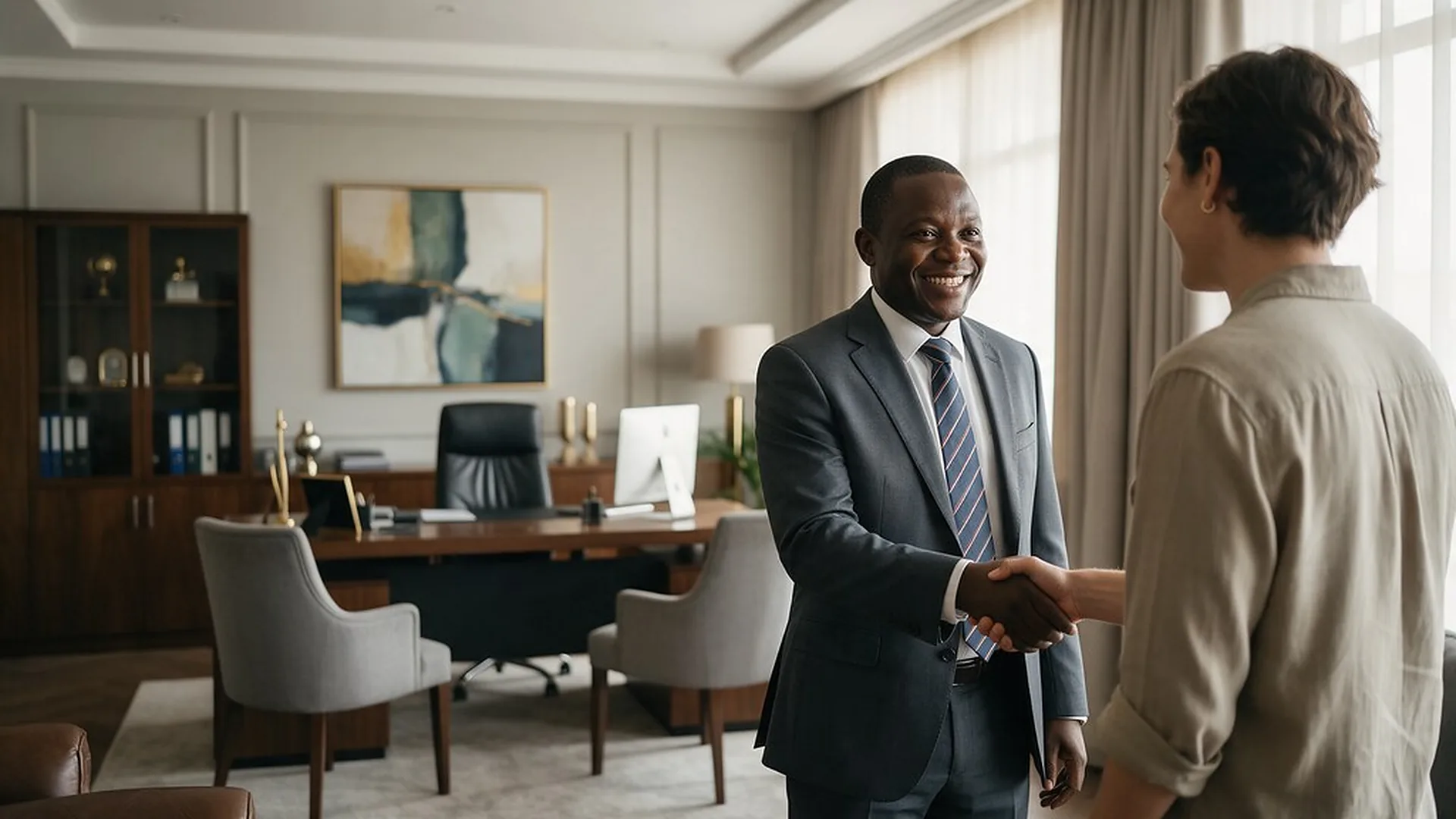 An executive welcoming a visitor with a handshake in a bright office